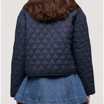 Person wearing a navy quilted jacket and denim skirt on a light gray background