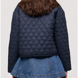 Person wearing a navy quilted jacket and denim skirt on a light gray background