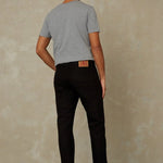 Man wearing a gray t-shirt and black pants against a beige wall