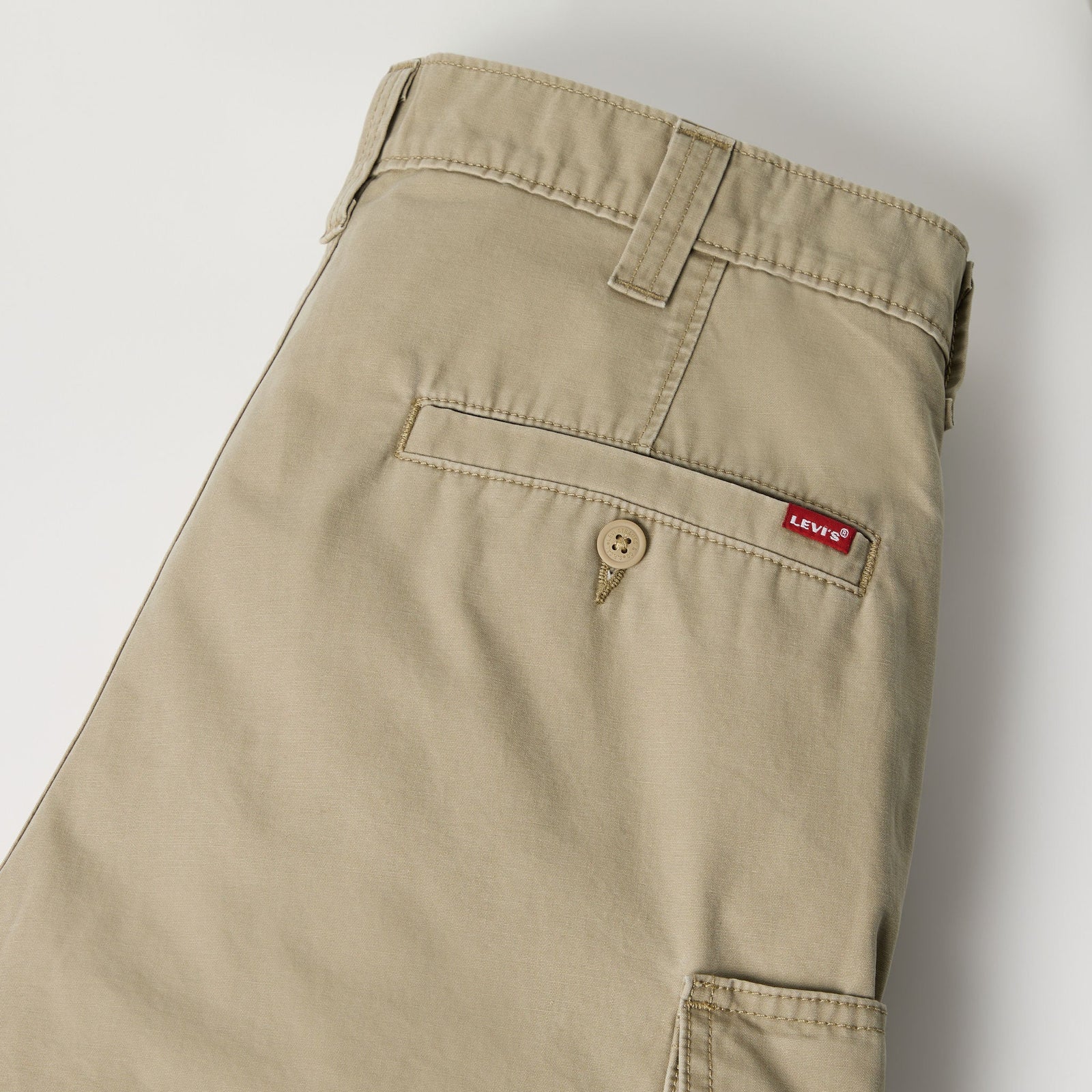 Close-up of the back waistband and pocket area of a pair of beige Levi's chino pants, showing the red Levi's brand tab on the back pocket.