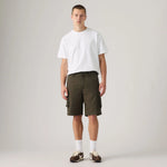 A male model stands against a light gray studio background wearing a plain white short-sleeve T-shirt, olive green cargo shorts, white socks, and brown sneakers.