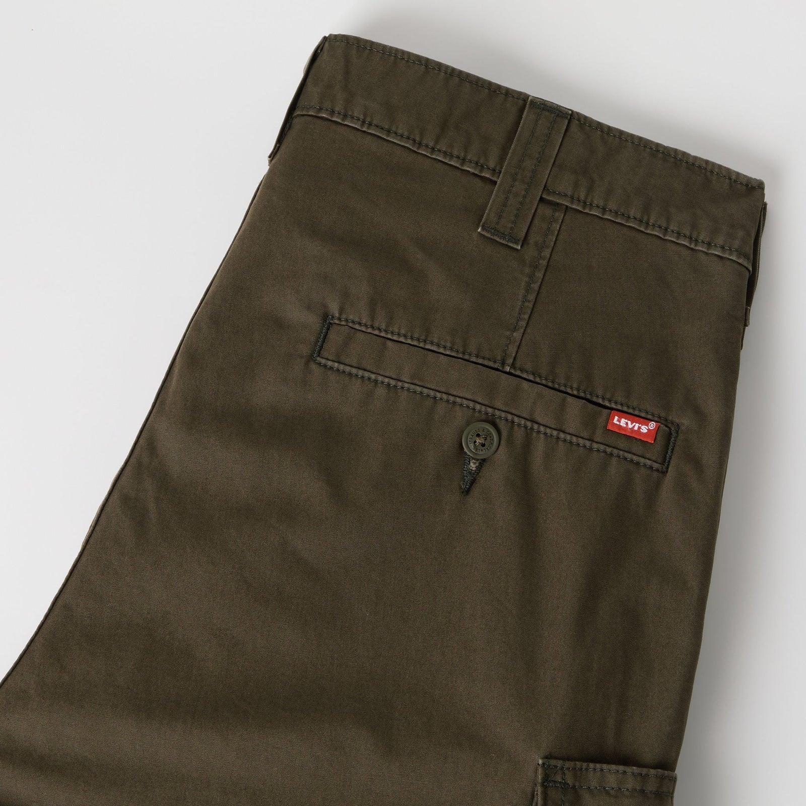 Close-up of dark olive green Levi's pants showing the back pocket with a button and the signature red Levi's tab.