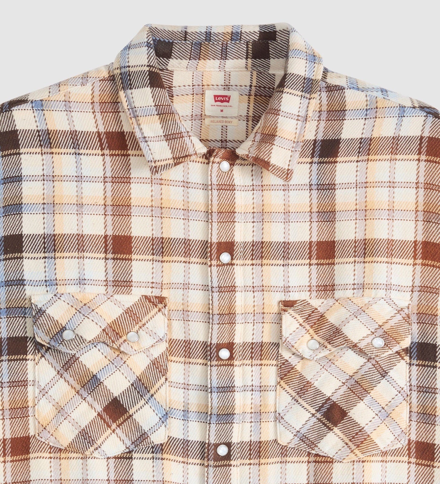 A close-up of a Levi's men's long-sleeve plaid button-down shirt. The fabric features a warm beige base with brown, black, and light blue plaid lines.