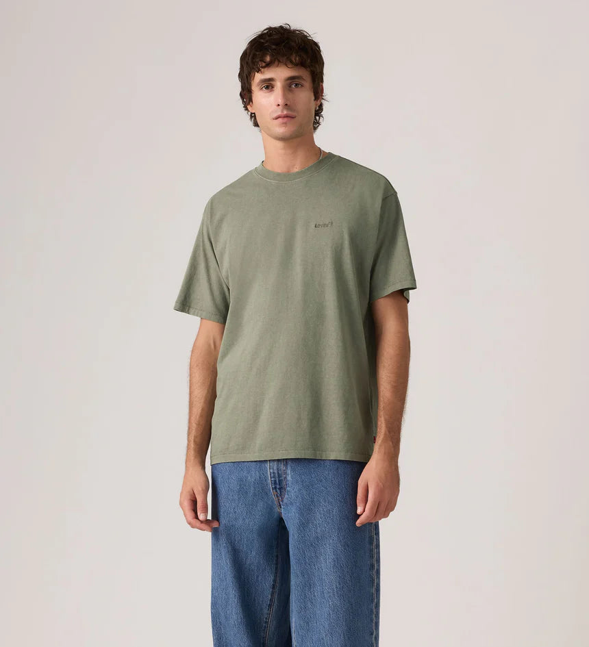 Person wearing a green t-shirt and blue jeans against a plain background