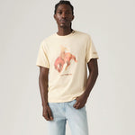 Man wearing a beige t-shirt with a graphic design on a plain background