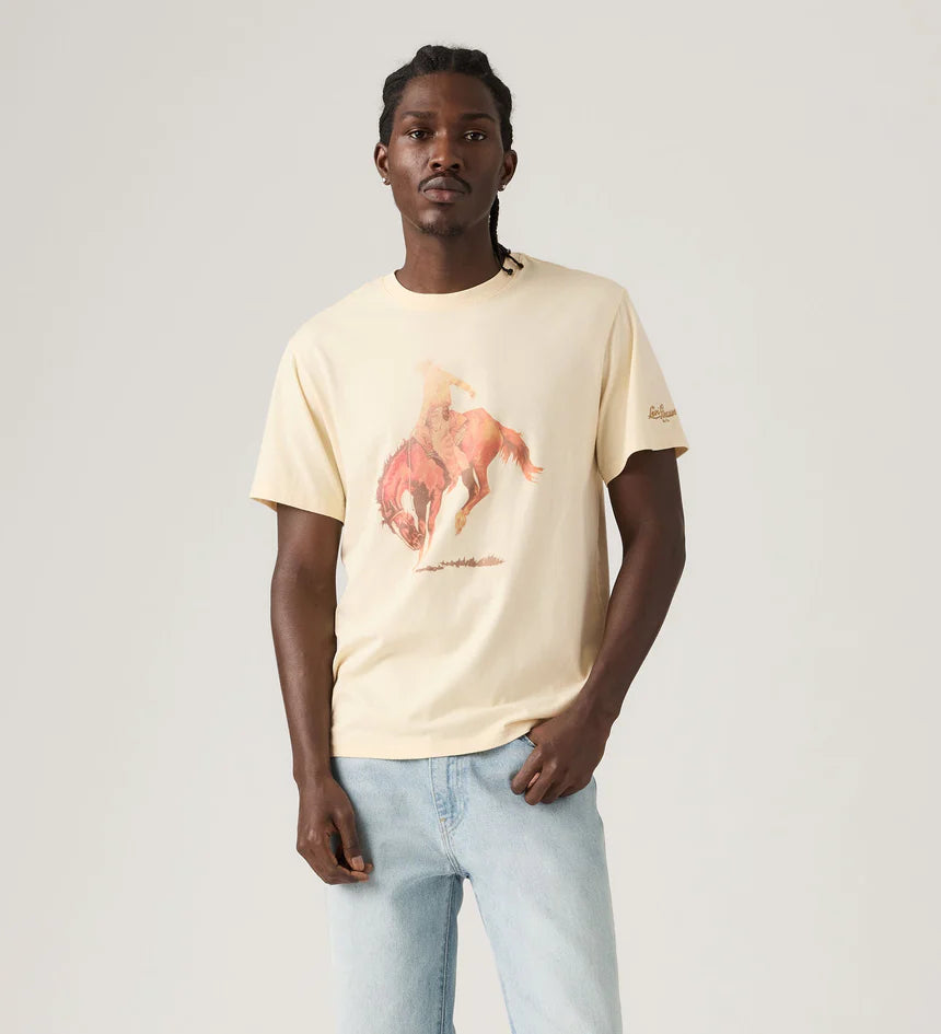 Man wearing a beige t-shirt with a graphic design on a plain background