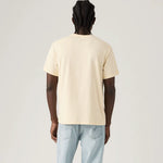 Person wearing a beige t-shirt and light blue jeans on a plain background