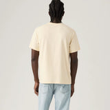 Person wearing a beige t-shirt and light blue jeans on a plain background
