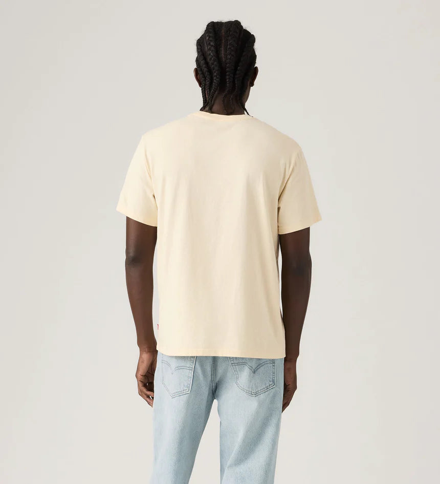 Person wearing a beige t-shirt and light blue jeans on a plain background