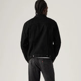 Person wearing a black jacket and dark jeans on a light gray background