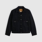 A black denim trucker jacket with a button-up front, two front flap pockets, and a classic collar, displayed flat against a light gray background.