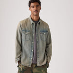 Man wearing a denim jacket and camouflage pants on a plain background