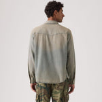 Man wearing a green denim shirt and camouflage pants on a white background