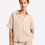 Woman wearing a beige linen shirt and pants on a white background