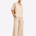 Woman wearing a beige linen outfit on a white background