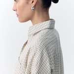 Woman wearing a checkered shirt with a plain background