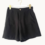 Black shorts on a hanger against a white background