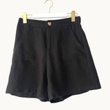 Black shorts on a hanger against a white background
