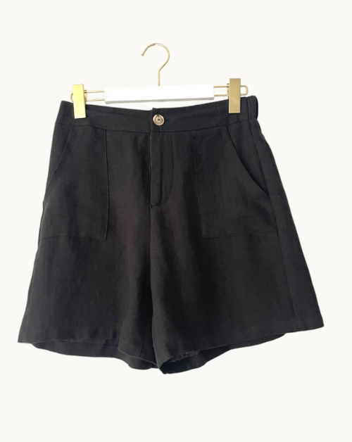Black shorts on a hanger against a white background