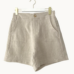 Beige shorts on a hanger against a white background