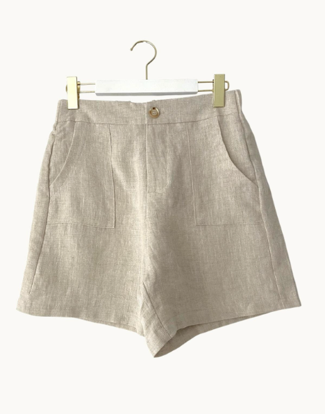 Beige shorts on a hanger against a white background