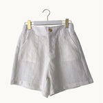 White linen shorts on a hanger against a white background