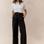 woman wearing black linen pants and stripe tee on a neautral background