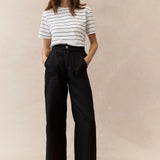 woman wearing black linen pants and stripe tee on a neautral background