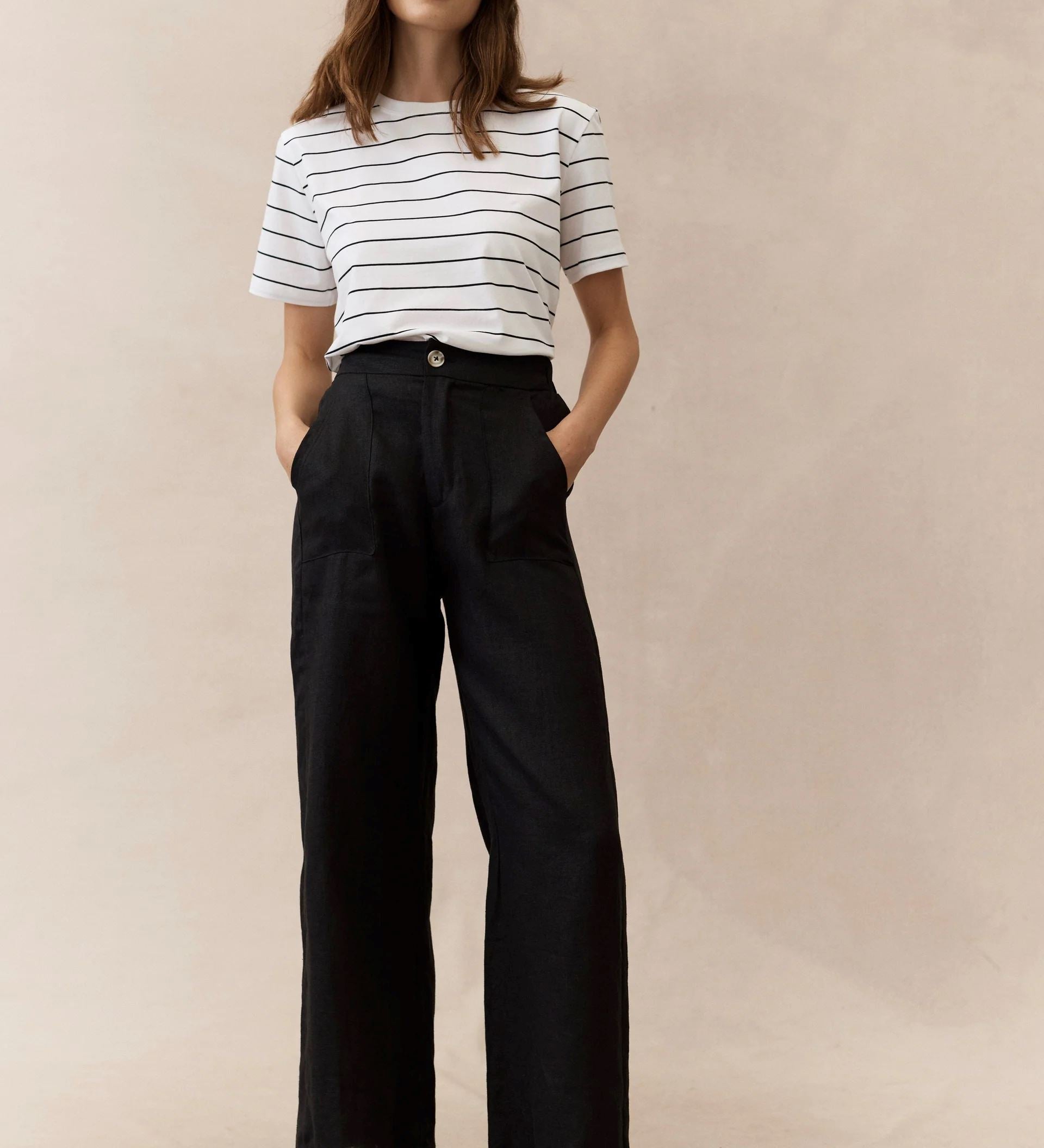 woman wearing black linen pants and stripe tee on a neautral background
