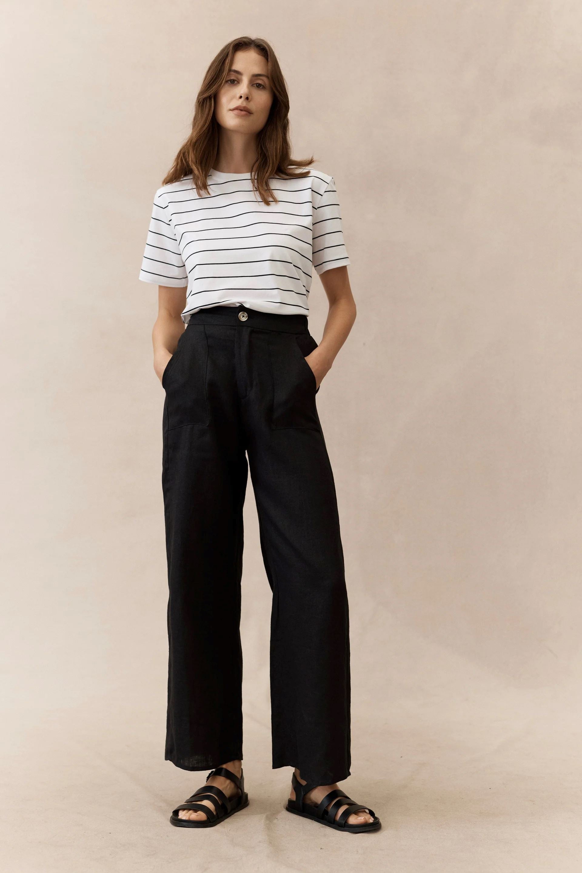 woman wearing black linen pants and stripe tee on a neautral background