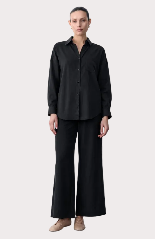 Person wearing a black outfit with text on the left side