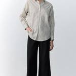 Person wearing a checkered shirt and black pants against a white background