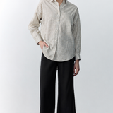 Person wearing a checkered shirt and black pants against a white background
