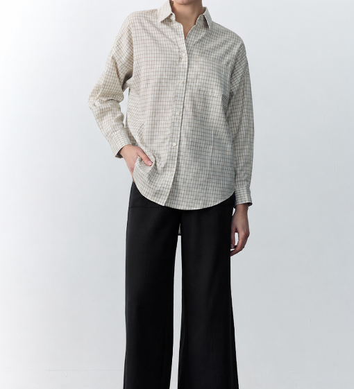 Person wearing a checkered shirt and black pants against a white background