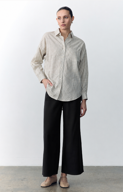 Person wearing a checkered shirt and black pants against a white background