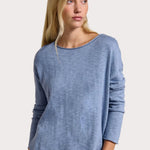 Woman wearing a blue sweater with product details on a beige background