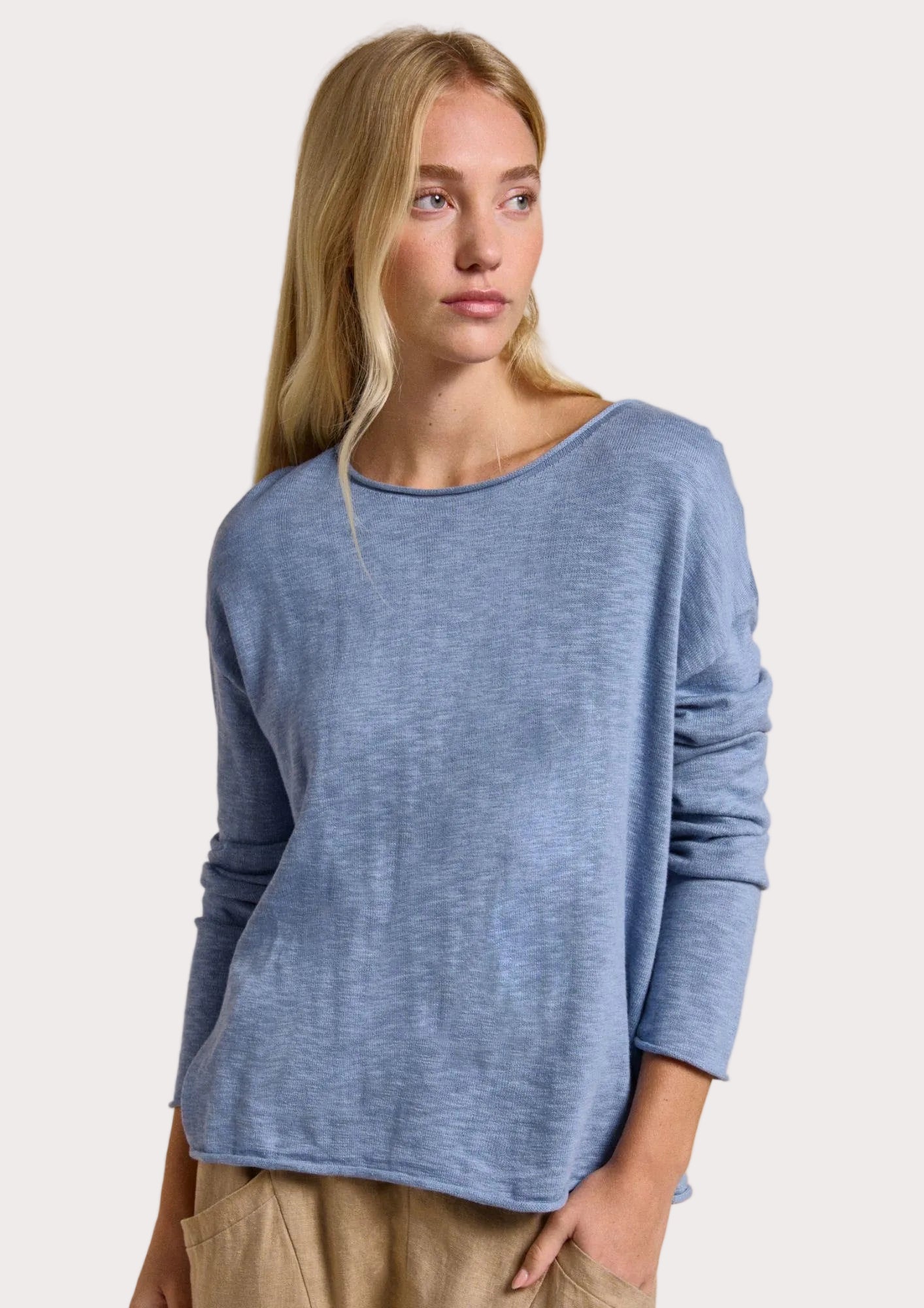 Woman wearing a blue sweater with product details on a beige background