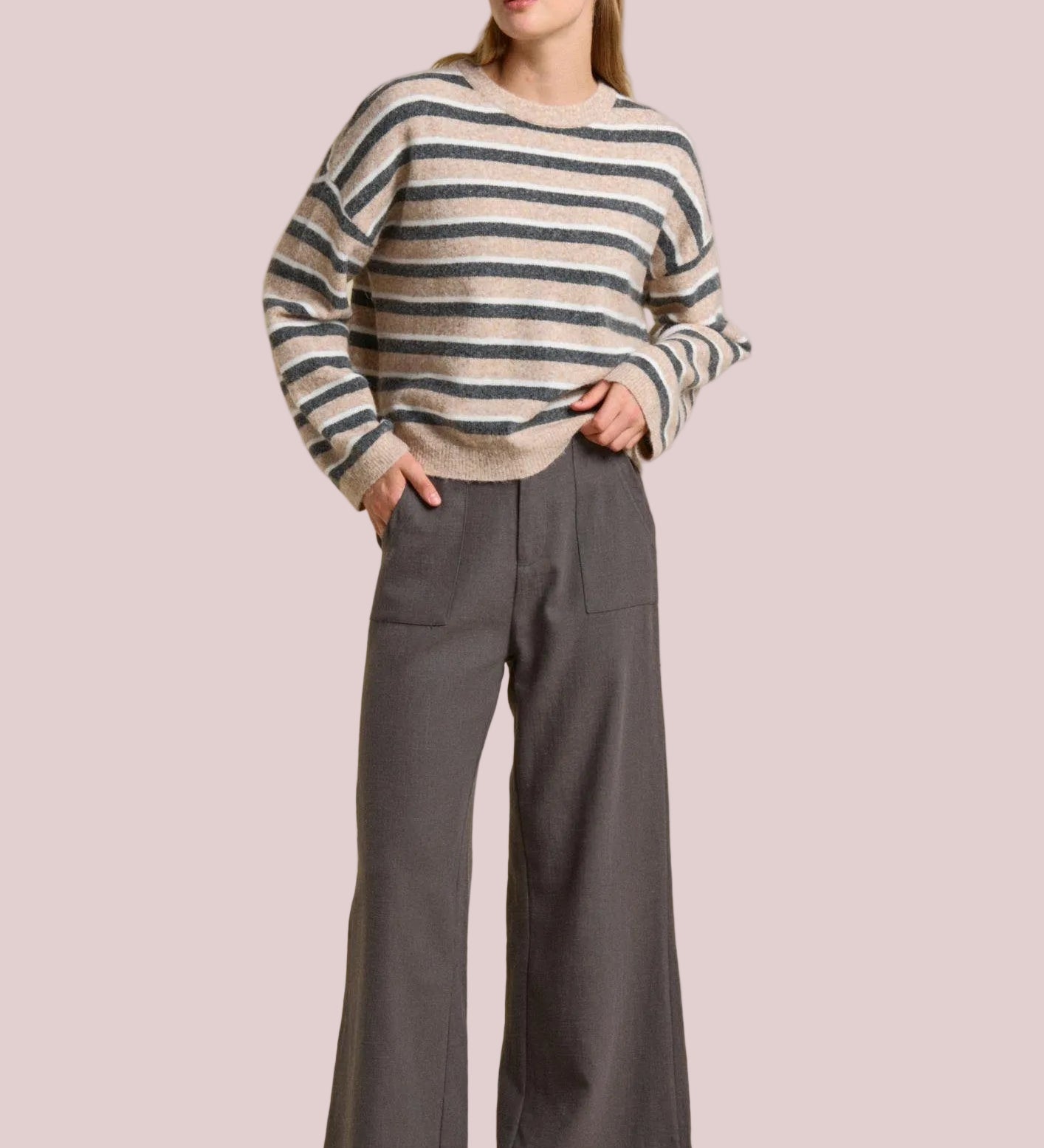 Woman wearing a striped sweater and gray pants on a beige background