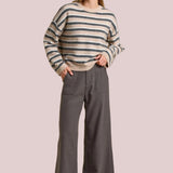Woman wearing a striped sweater and gray pants on a beige background