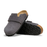 A pair of dark gray suede clogs with a black treaded sole and a natural cork back, displayed on a clean white background.