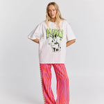 Person wearing a white oversized t-shirt with a graphic design and red striped pants on a white background