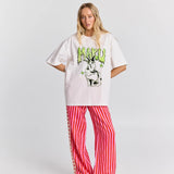 Person wearing a white oversized t-shirt with a graphic design and red striped pants on a white background