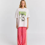 Person wearing a white oversized t-shirt with graphic design and red striped pants on a white background