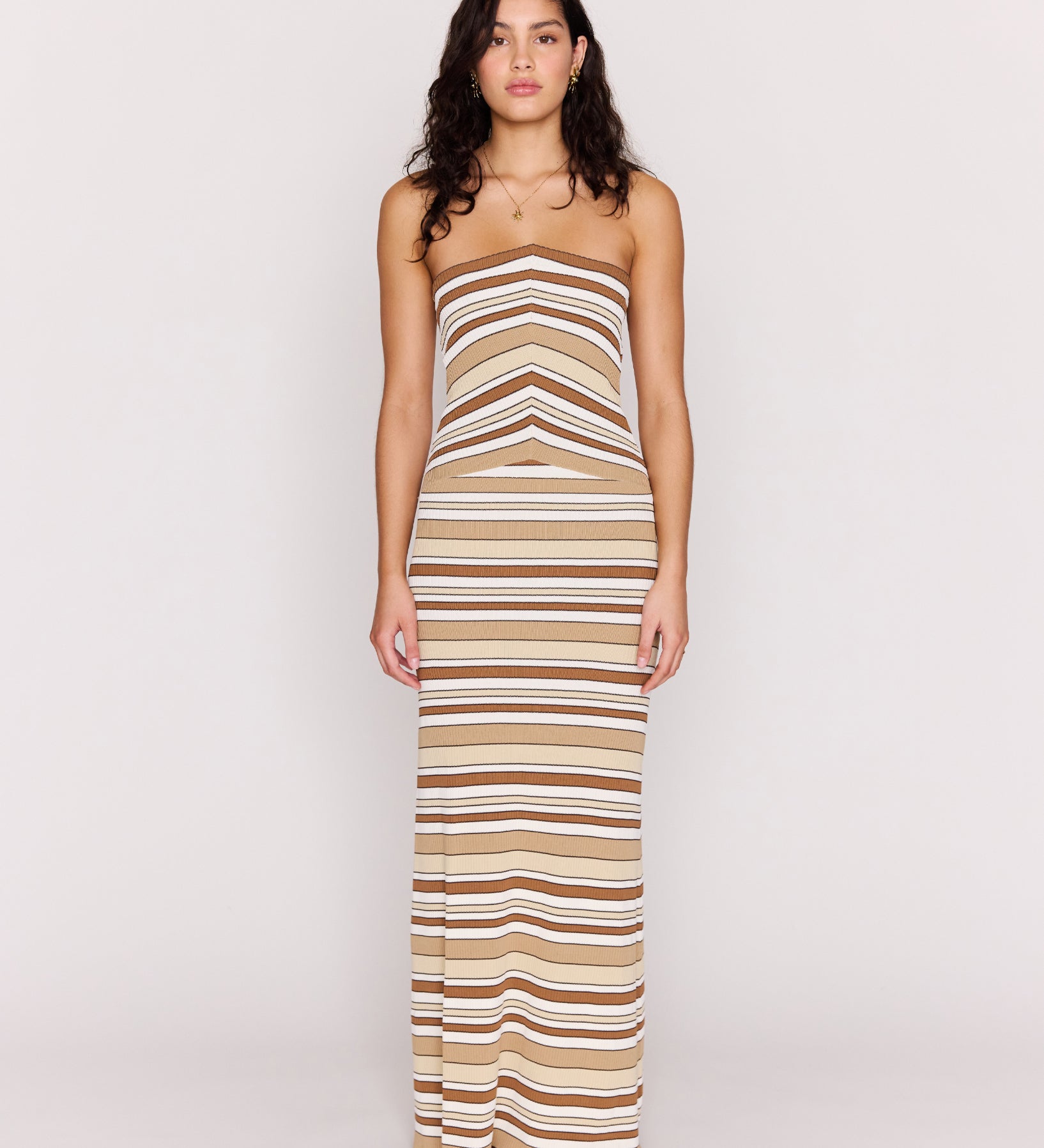 Woman wearing a strapless, long, striped dress on a white background