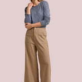 Woman wearing a blue sweater and beige pants on a beige background