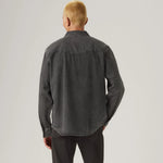 Person wearing a dark gray shirt and pants on a light gray background
