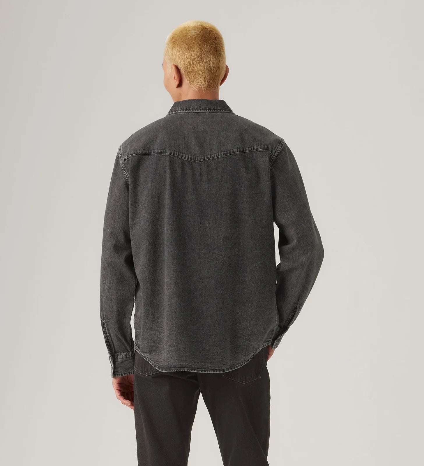 Person wearing a dark gray shirt and pants on a light gray background