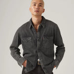 Man wearing a dark gray denim shirt against a plain background