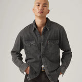Man wearing a dark gray denim shirt against a plain background
