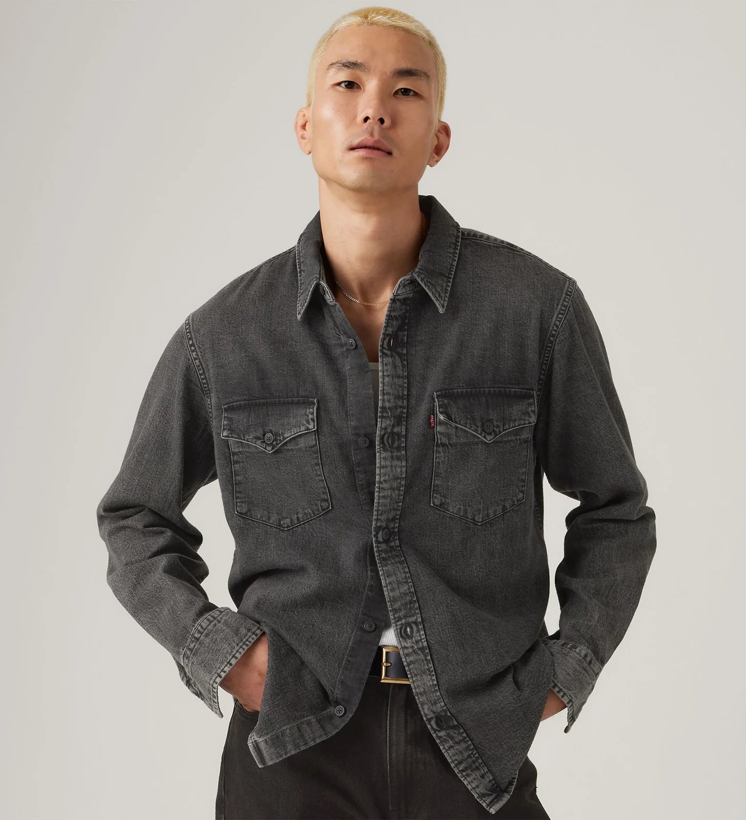 Man wearing a dark gray denim shirt against a plain background